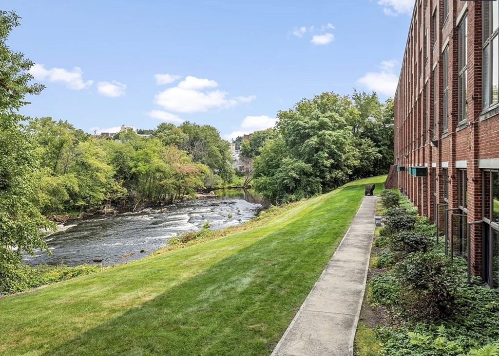 128 Warren Street, Unit 12 Lowell, MA 01852 - Photo 22 of 24 a view of a yard with flower plants and wooden fence