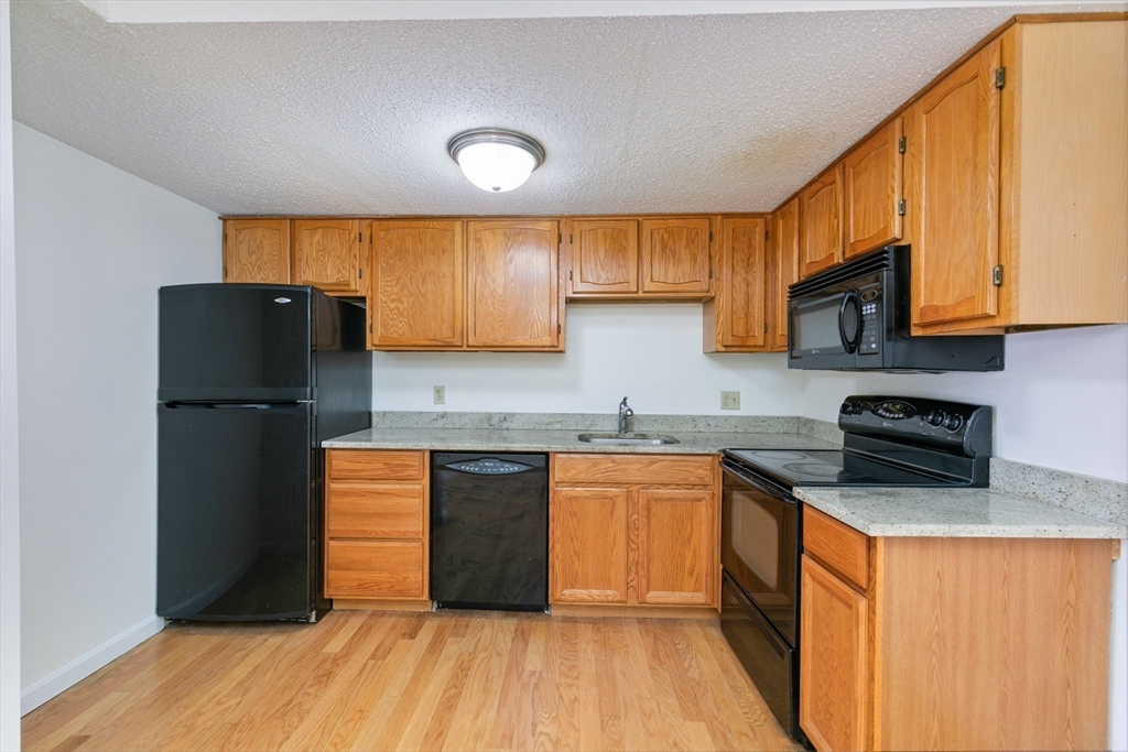 128 Warren Street, Unit 12 Lowell, MA 01852 - Photo 6 of 24 a kitchen with stainless steel appliances granite countertop a refrigerator a sink dishwasher a stove top oven a refrigerator and cabinets with wooden floor
