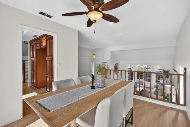 a kitchen with stainless steel appliances granite countertop a stove top oven a sink dishwasher a dining table and chairs with wooden floor