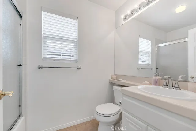 a bathroom with a granite countertop toilet a sink a mirror and a window