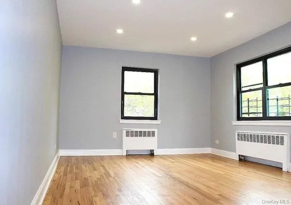 a view of an empty room with a window and wooden floor