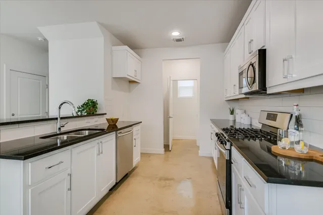 a kitchen with stainless steel appliances granite countertop a sink stove and cabinets