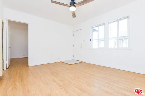 an empty room with wooden floor and fan
