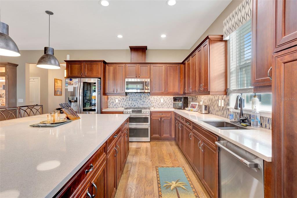 176 Silver Maple Road Groveland, FL 34736 - Photo 11 of 45 a kitchen with stainless steel appliances kitchen island granite countertop a sink a stove and a refrigerator