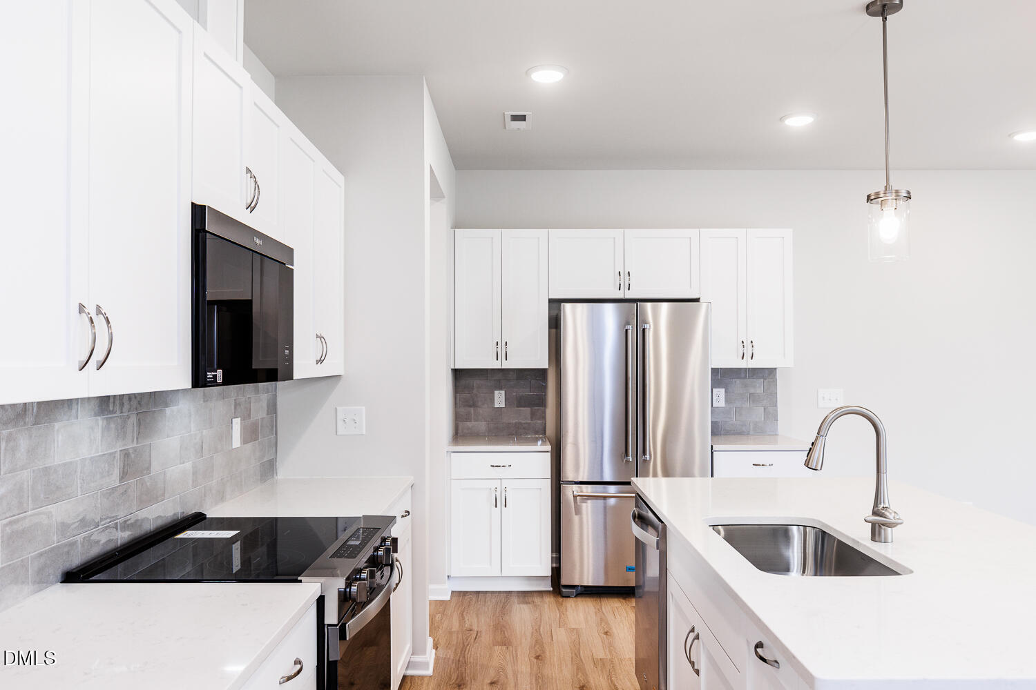 136 Siebold Street Garner, NC 27529 - Photo 18 of 43 a kitchen with stainless steel appliances a refrigerator a sink a stove and white cabinets with wooden floor