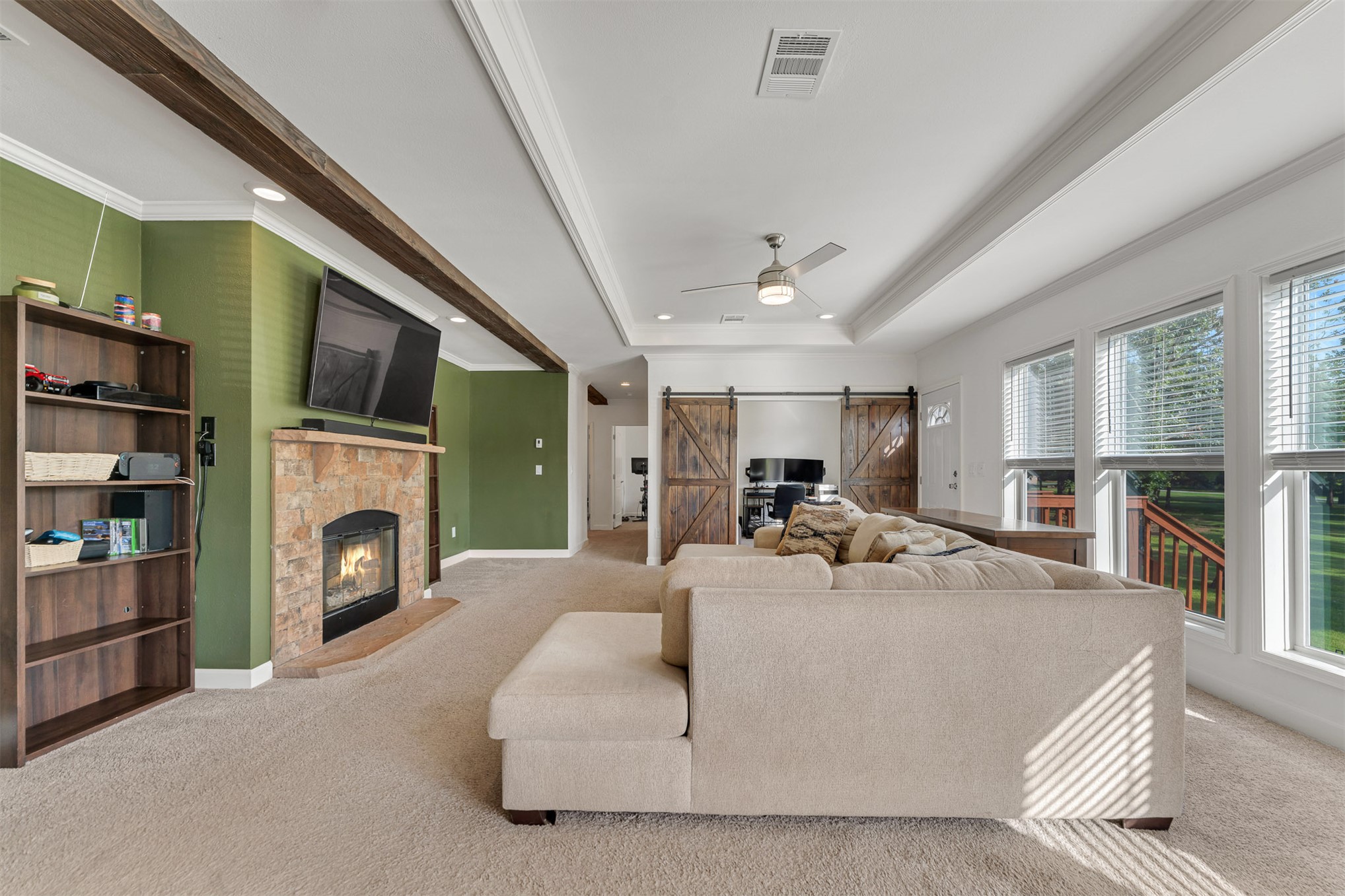 15291 East 400 Road Claremore, OK 74017 - Photo 26 of 96 Spacious living area featuring a stone-clad fireplace, wood-finish ceiling beams, and multiple windows