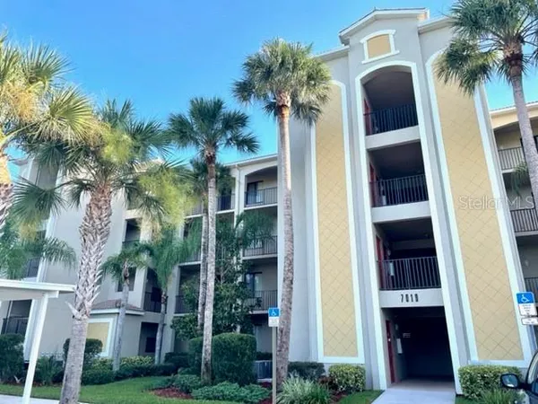 a front view of multi story residential apartment building with yard and parking
