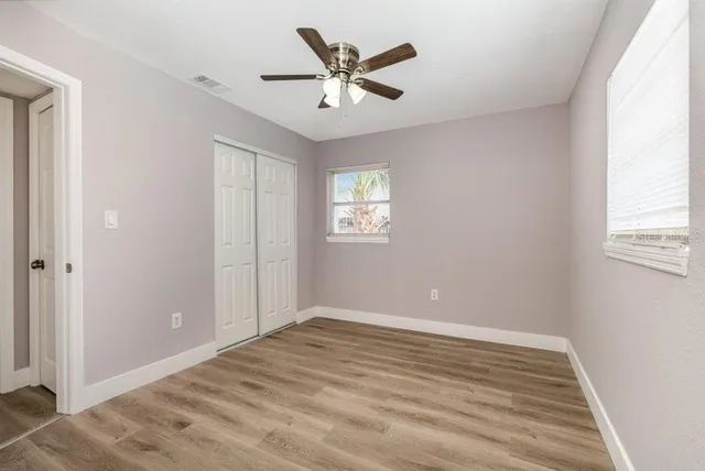 a view of empty room with wooden floor and ceiling fan