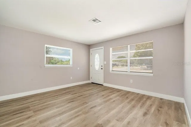 a view of an empty room with wooden floor and a window