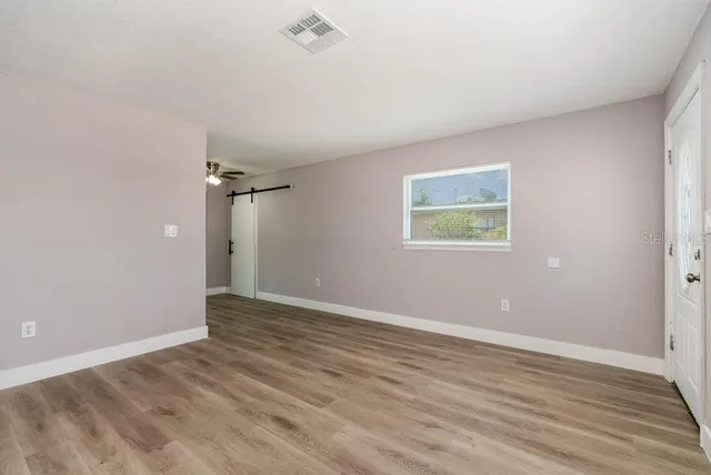 an empty room with wooden floor and windows