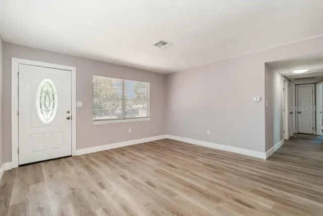 an empty room with wooden floor cabinet and windows