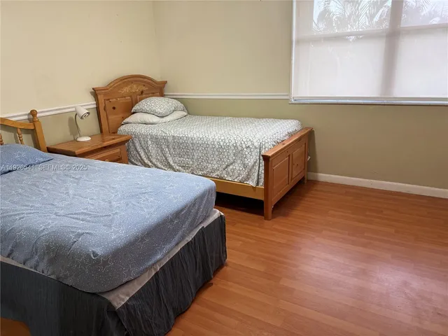 a bedroom with two beds and wooden floor