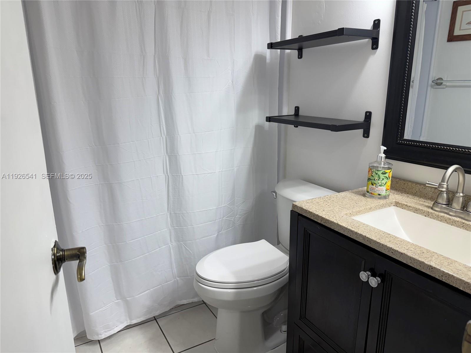 9901 Northwest 9th St Circle, Unit 32 Miami, FL 33172 - Photo 12 of 14 a bathroom with a granite countertop sink toilet and mirror