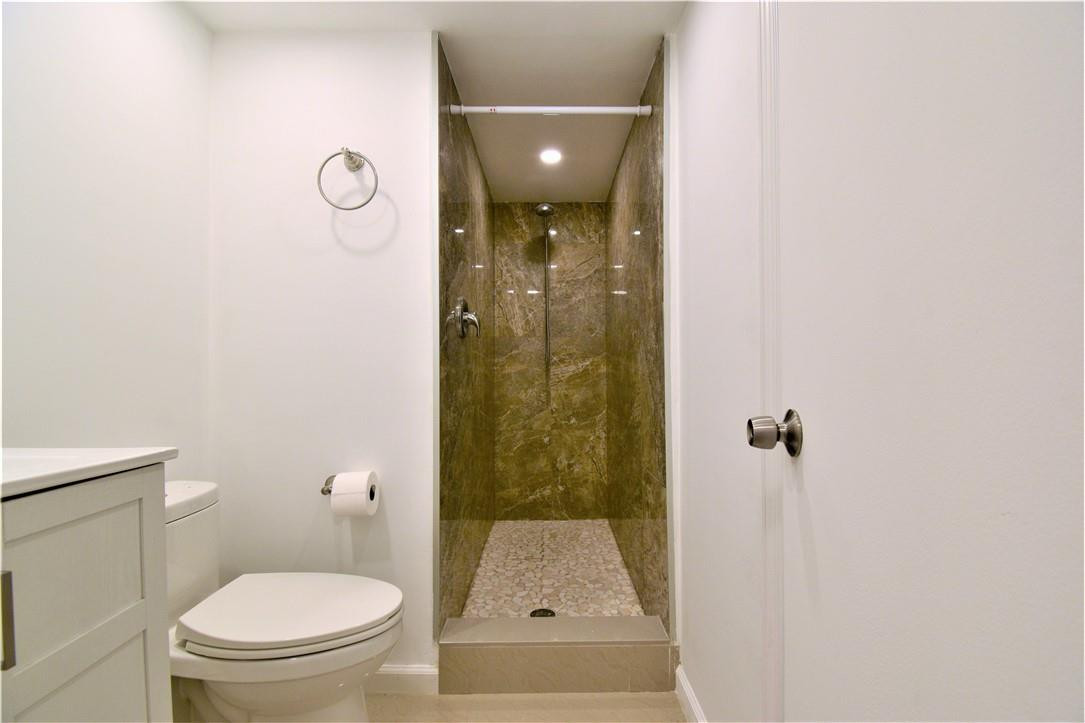 9273 Southwest 8th Street, Unit 407 Boca Raton, FL 33428 - Photo 12 of 19 a bathroom with a granite countertop toilet a sink and shower