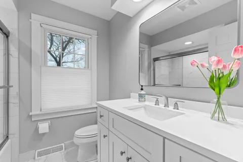 a bathroom with a sink a mirror a toilet and a window