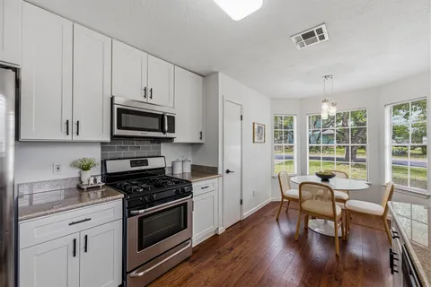 a kitchen with stainless steel appliances a stove a table and chairs