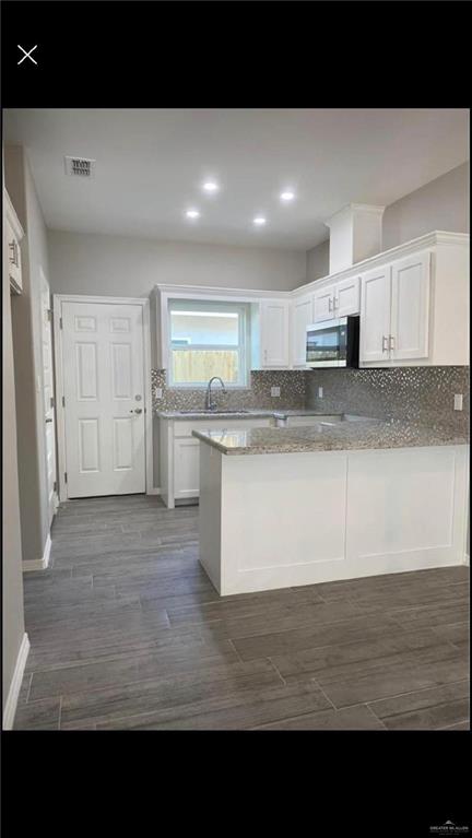 2104 Stauffers Street Weslaco, TX 78596 - Photo 4 of 12 Kitchen with decorative backsplash, white cabinetry, stainless steel microwave, a peninsula, and recessed lighting