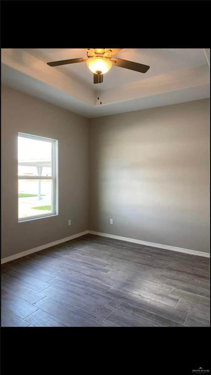 2104 Stauffers Street Weslaco, TX 78596 - Photo 9 of 12 Unfurnished room featuring light wood-style flooring, a tray ceiling, and ceiling fan