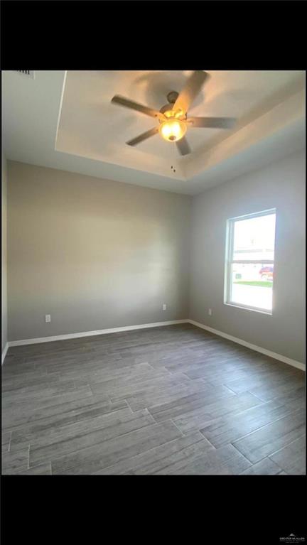 2104 Stauffers Street Weslaco, TX 78596 - Photo 10 of 12 Empty room featuring a raised ceiling, light wood-type flooring, and a ceiling fan