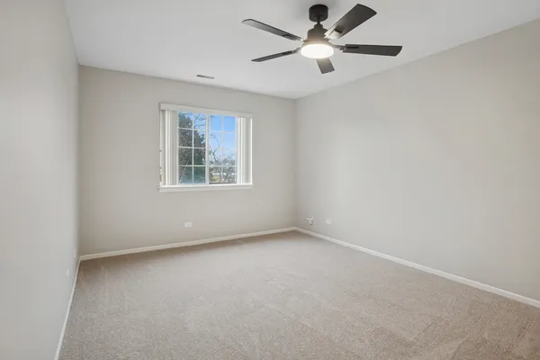 an empty room with ceiling fan and window