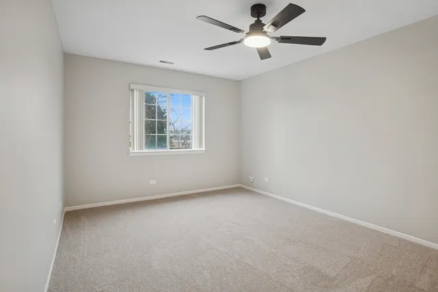 an empty room with ceiling fan and window