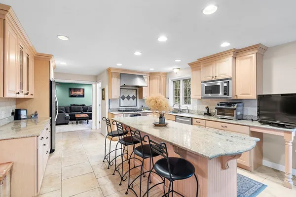 a room with stainless steel appliances kitchen island granite countertop a stove a sink a oven a dining table and chairs