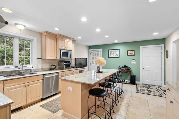 a open kitchen with stainless steel appliances granite countertop a sink a stove a dining table and chairs