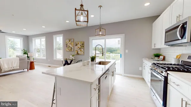 a kitchen with stainless steel appliances a sink a stove a refrigerator cabinets and living room view