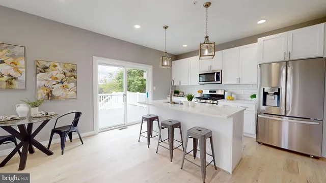 a kitchen with stainless steel appliances granite countertop a refrigerator a microwave a stove a sink dishwasher a dining table and chairs with wooden floor