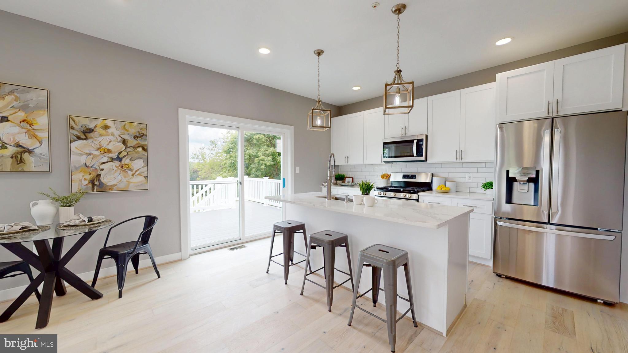 6516 Golden Ring Road Rosedale, MD 21237 - Photo 8 of 32 a kitchen with stainless steel appliances granite countertop a refrigerator a microwave a stove a sink dishwasher a dining table and chairs with wooden floor