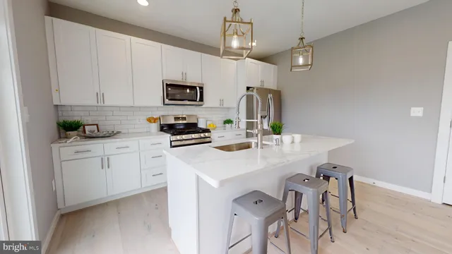 a kitchen with stainless steel appliances a sink a stove a refrigerator cabinets and a dining table