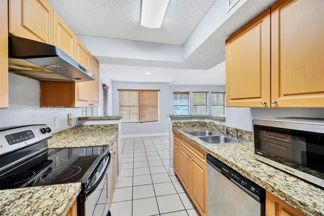 a kitchen with stainless steel appliances granite countertop a stove a sink and a microwave
