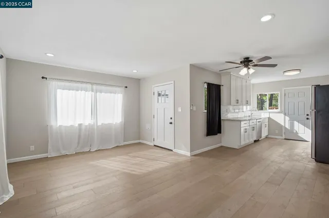 a view of a big room with windows and a ceiling fan