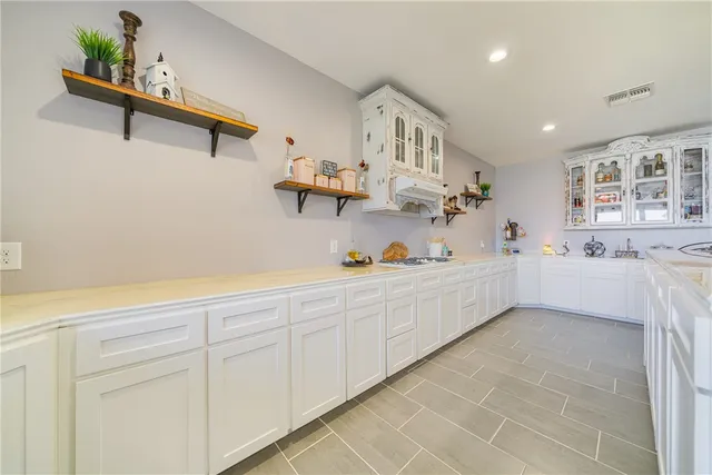 a large white kitchen with sink and cabinets