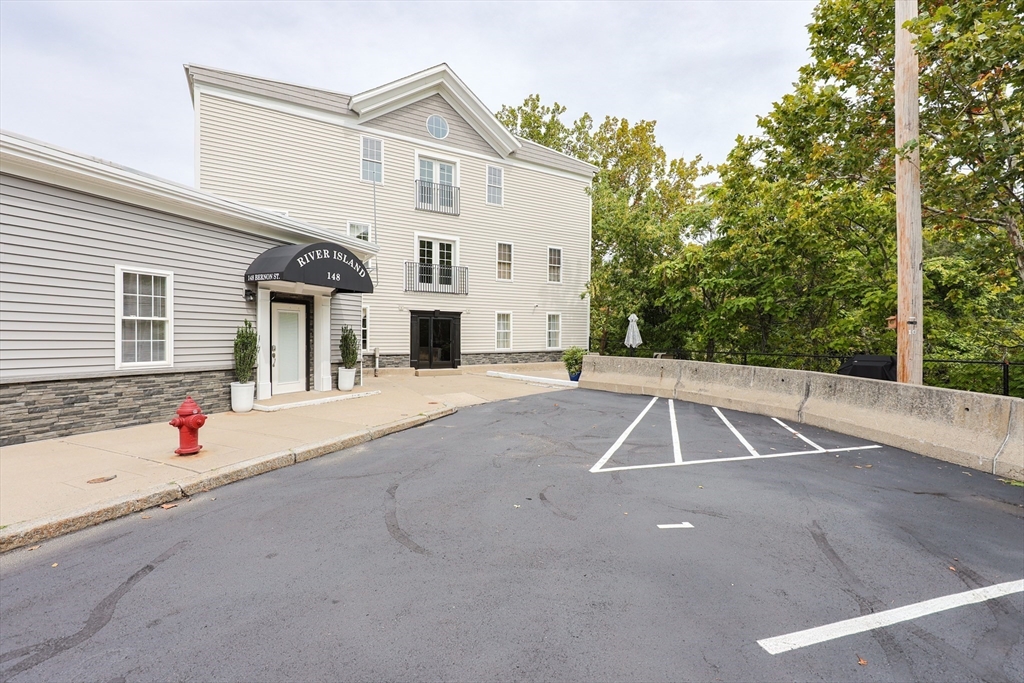 148 Bernon Street, Unit 19 Woonsocket, RI 02895 - Photo 18 of 20 a view of a white house with a yard and garage