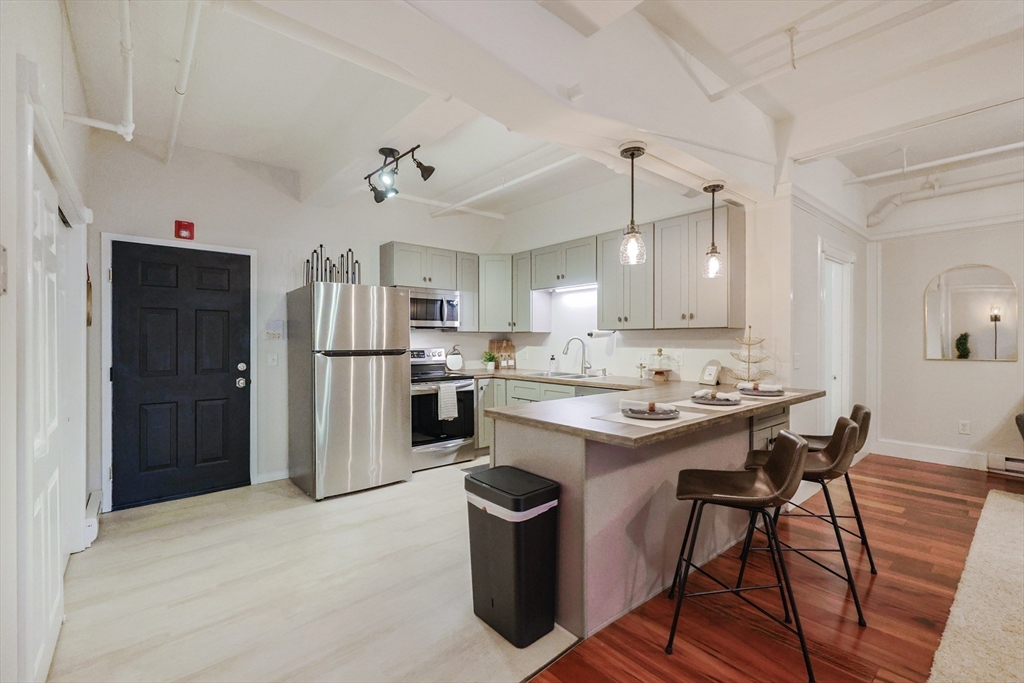 148 Bernon Street, Unit 19 Woonsocket, RI 02895 - Photo 4 of 20 a kitchen with refrigerator a sink and chairs