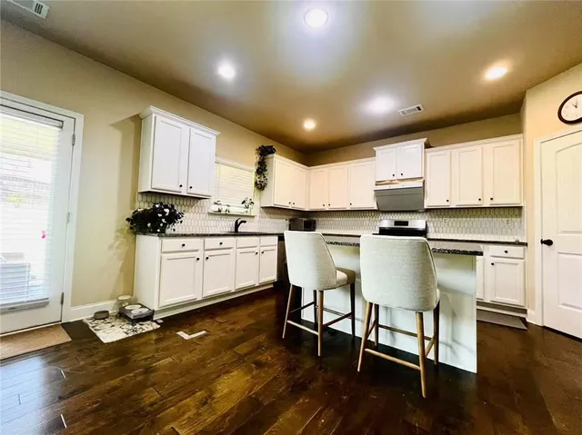 a kitchen with a sink chairs and wooden floor