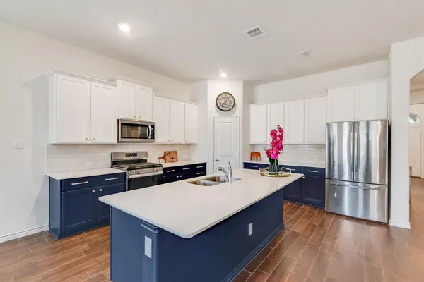 a kitchen with stainless steel appliances a sink a stove a refrigerator and cabinets