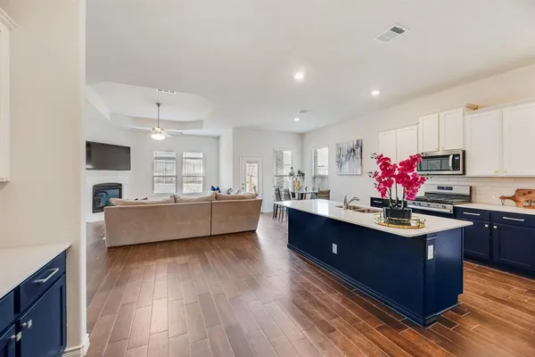 a kitchen with stainless steel appliances kitchen island granite countertop wooden floors granite counter tops and a window