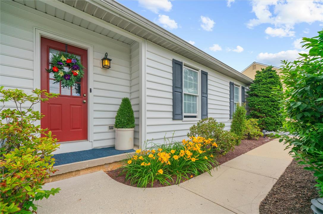5616 Snowdrift Road Orefield, PA 18069 - Photo 4 of 36 A vibrant red entry door welcomes you to this charming home, bordered by blooming yellow daylilies and verdant shrubs.