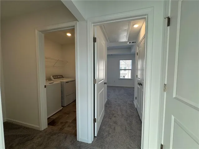 a view of a hallway with wooden floor and a bathroom
