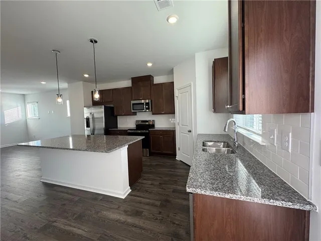 a large kitchen with kitchen island a large counter top a sink and a stove