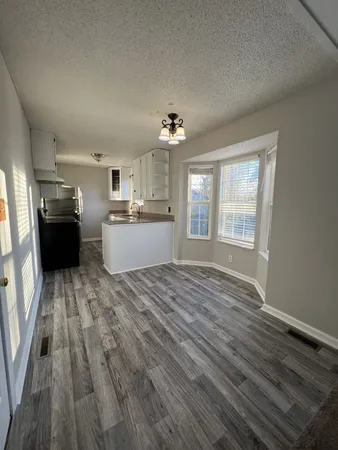 a view of a kitchen with wooden floor and stainless steel appliances