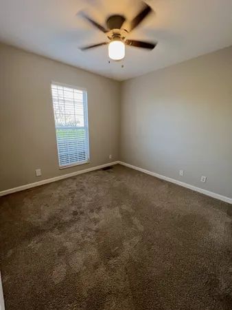 an empty room with windows and fan