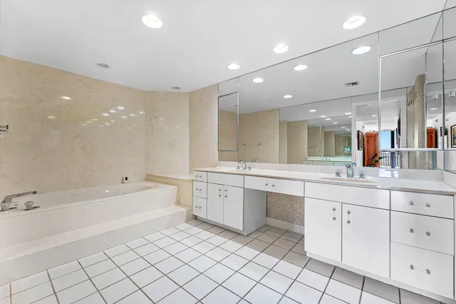 a large white bathroom with a large mirror vanity and a bathtub