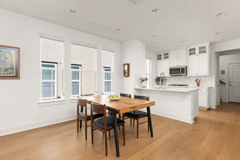 a kitchen with stainless steel appliances kitchen island granite countertop a stove a sink a dining table and chairs
