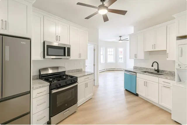 a kitchen with stainless steel appliances a sink stove oven and white cabinets