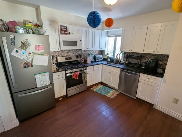 a kitchen with stainless steel appliances granite countertop a refrigerator a stove top oven a sink and dishwasher with wooden floor