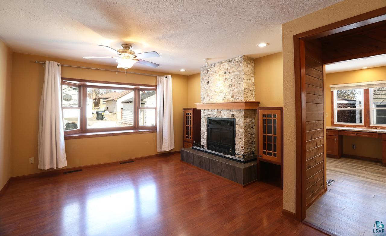 811 7th Street North Virginia, MN 55792 - Photo 11 of 37 Unfurnished living room with ceiling fan, wood finished floors, a textured ceiling, and a fireplace