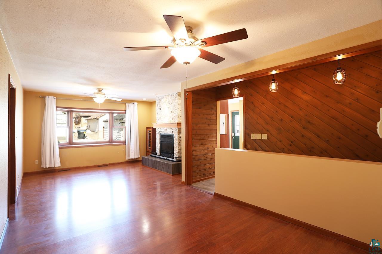 811 7th Street North Virginia, MN 55792 - Photo 13 of 37 Unfurnished living room featuring wood finished floors, a ceiling fan, a tile fireplace, and a textured ceiling